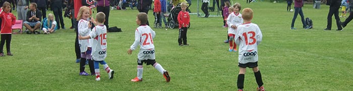 barn spiller fotball på gressmatte